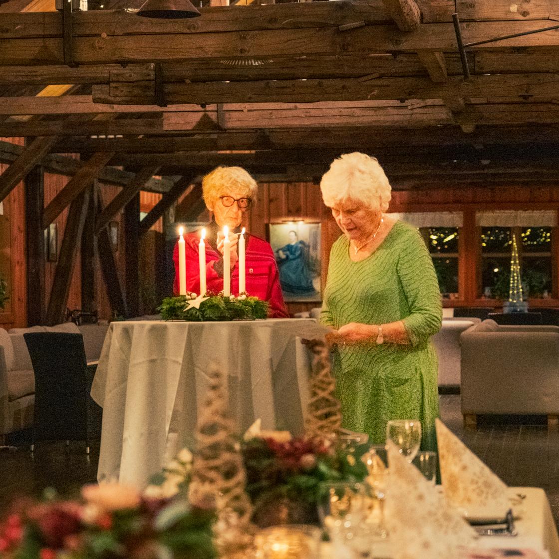 Ragnild Wold Hansen og Solveig Fjereide tenner adventslys og leser versene fra Inger Hagerup.