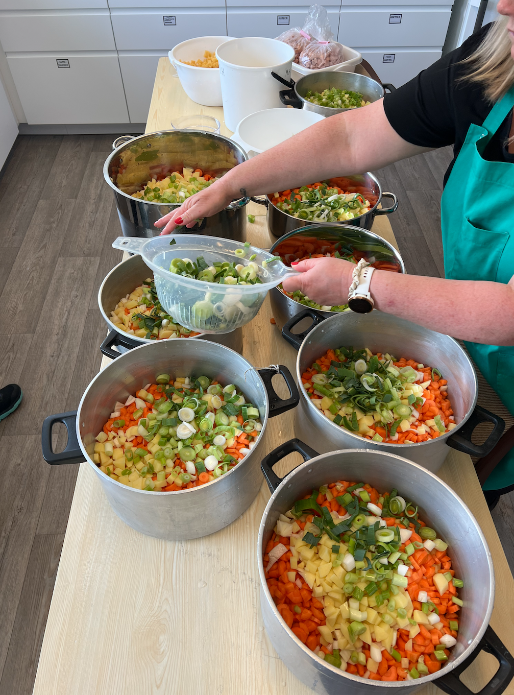 Grønnsaker og kjøtt er kuttet opp og fordeles i kasseroller. 85 liter kjøttsuppe til 17. mai feiring.
