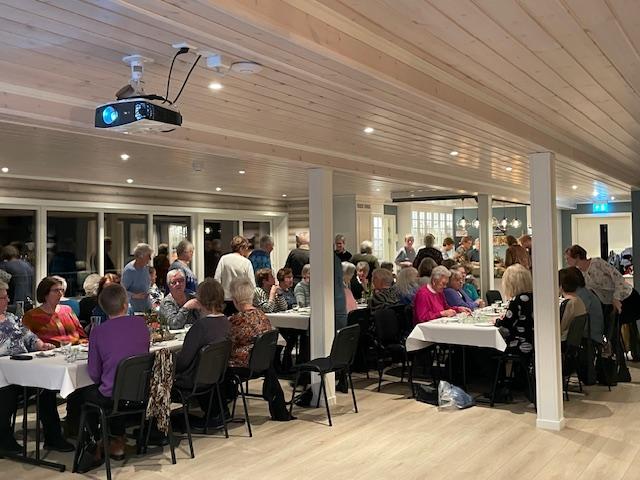 Mange bygdekvinner ved dekka bord i "Fjøsen" i Kleppeneset