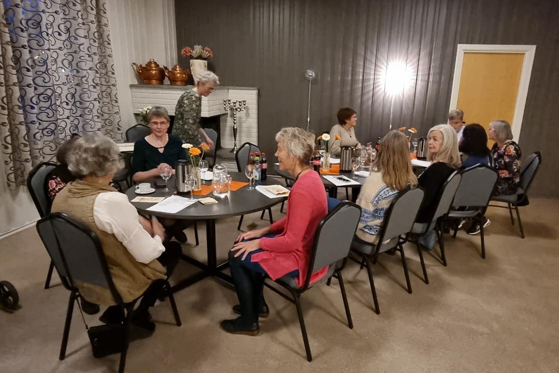 Mennesker sitter rundt et bord og snakker