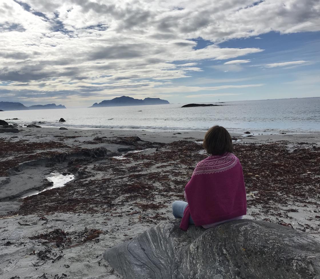 Strand, sand, flott himmel og Bjørg poserer.