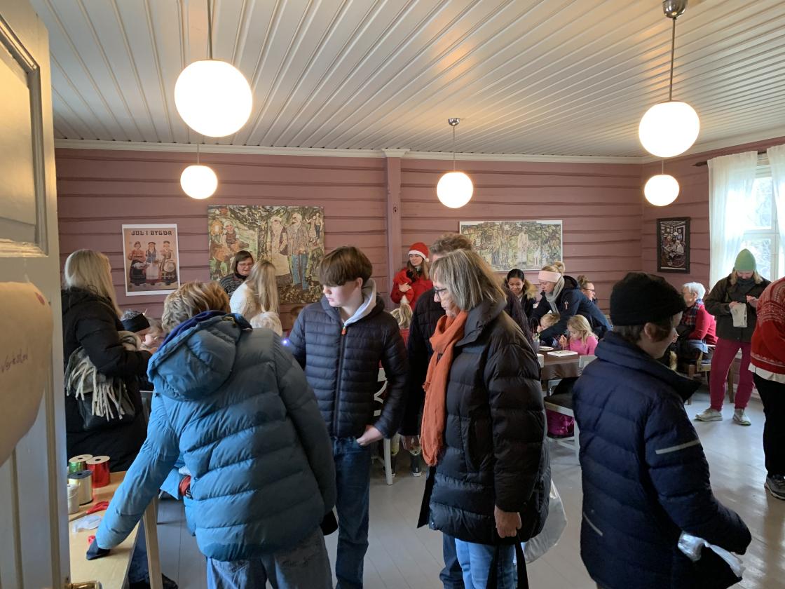 Fullt i skolestua, voksne varmer seg mens de venter på kreative unger