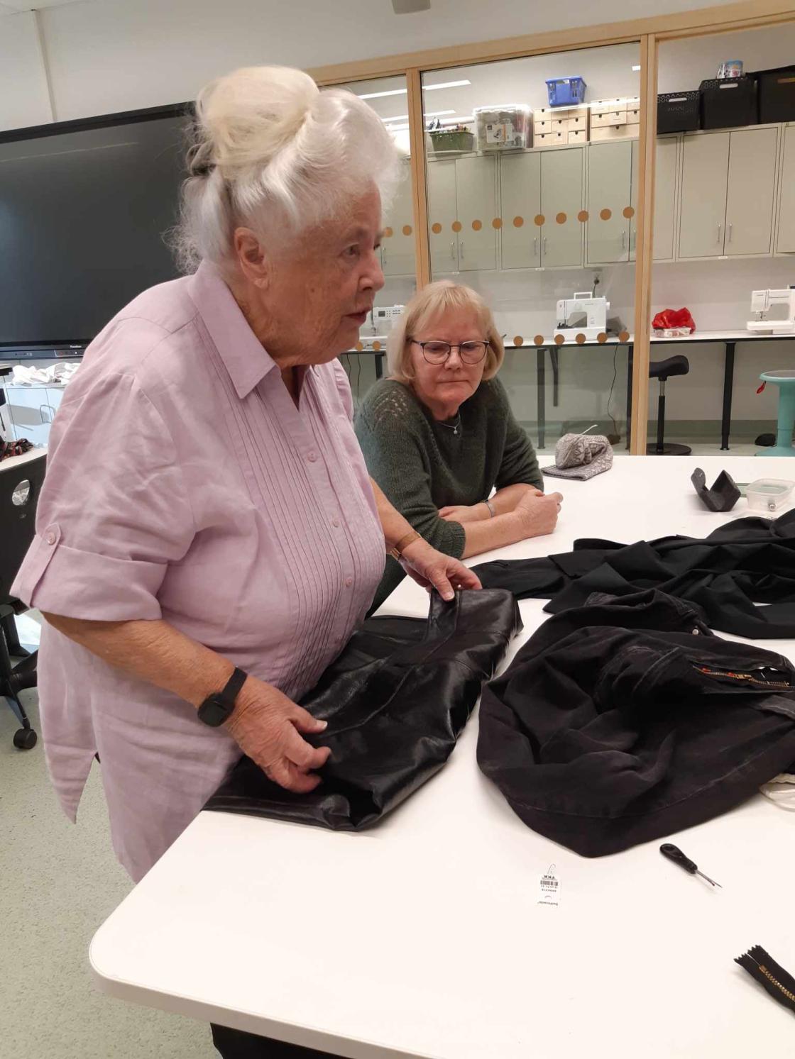 Kvinner prater om sying og viser på stoff