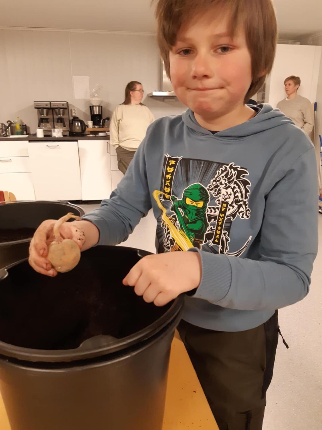 Barn setter en potet i en stor potte