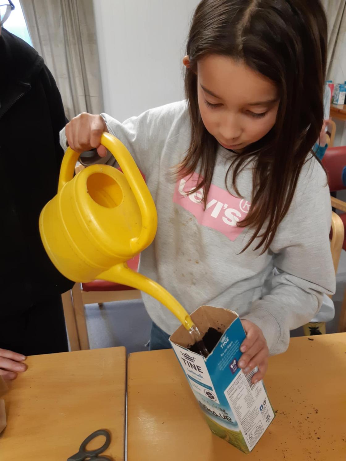 Barn vanner jorden i en melkekartong