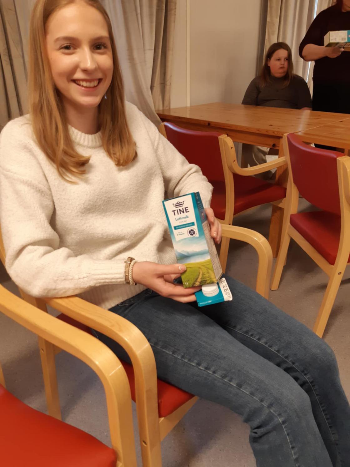 Jente smiler og viser frem en melkekartong for frøsåing