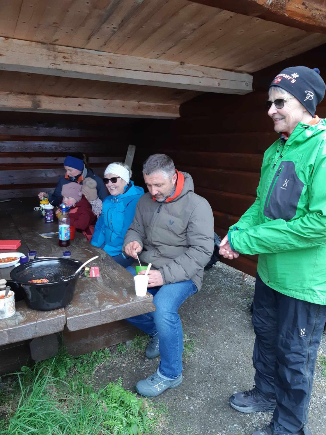 Turfølge sitter ved bord i gapahuk