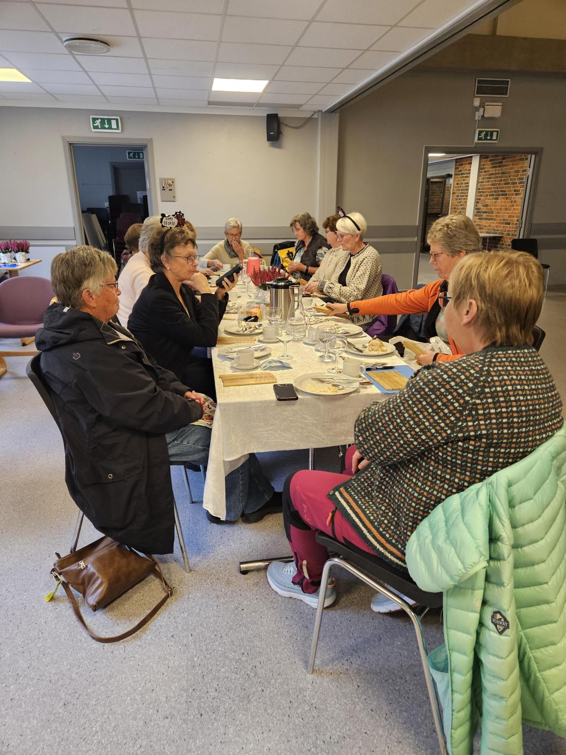 Kvinner samla rundt eit bord med kakeservering