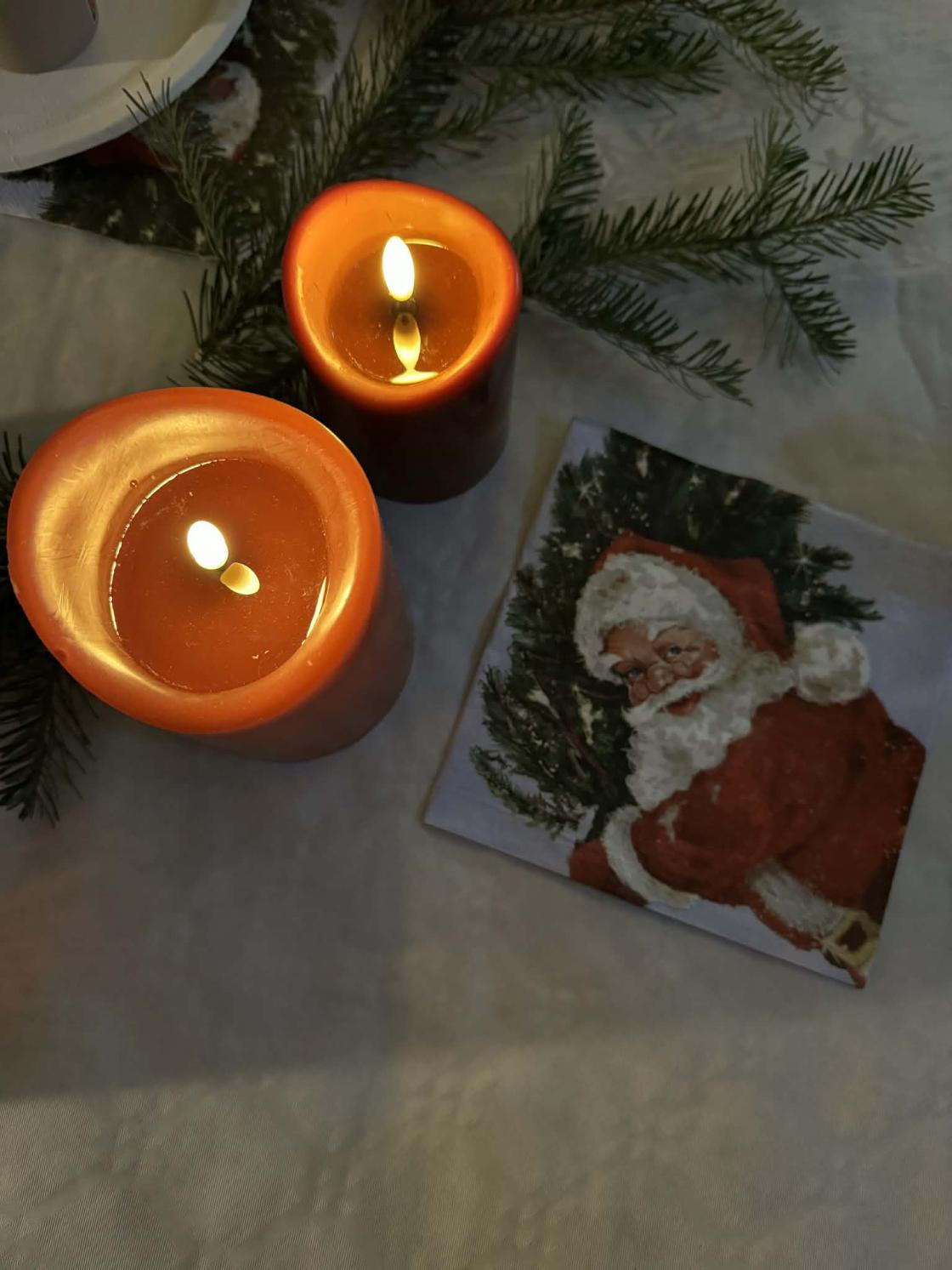 To stearinlys og serviett med julenisse