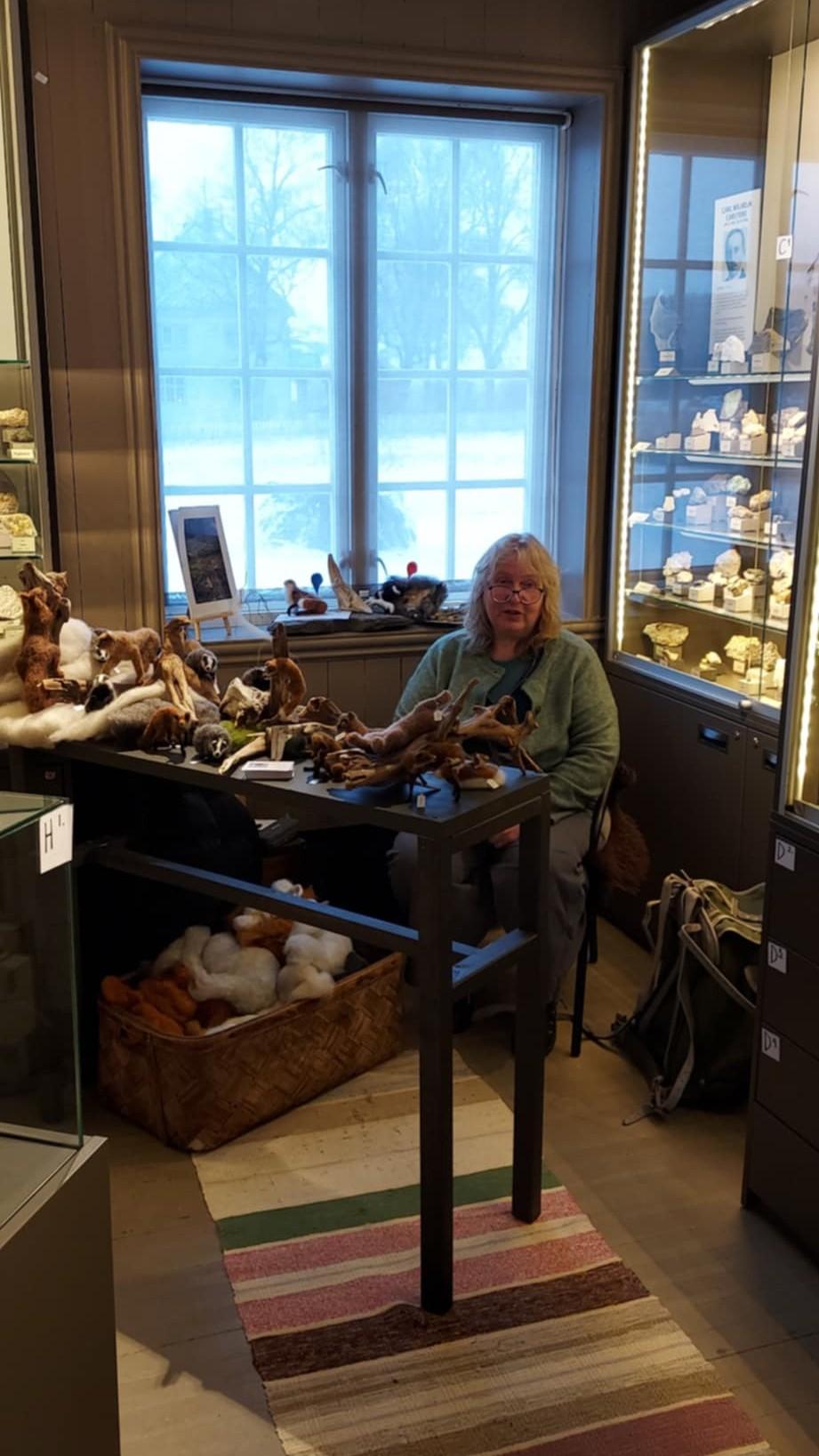 kvinne sitter ved utstilling av ulldyr