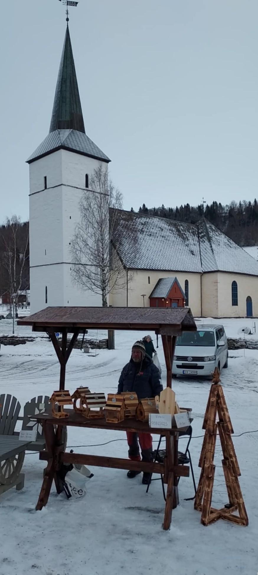Salgsbod med trevarer med Selbu kirke i bakgrunn