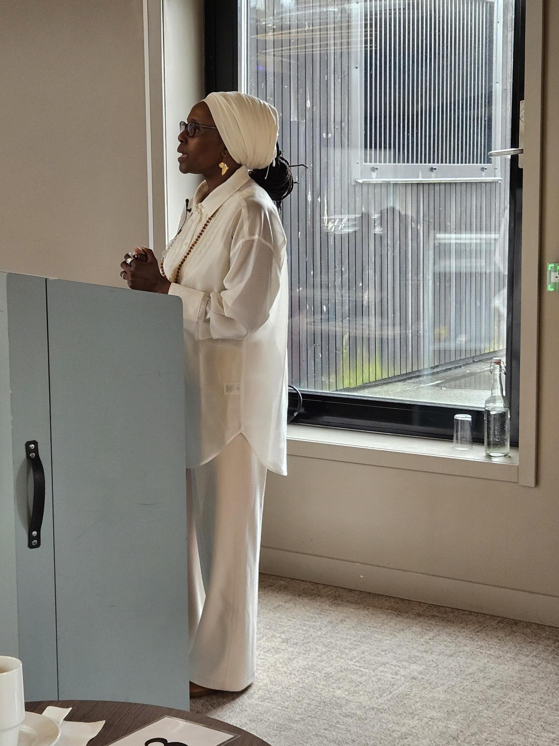 Mørk dame i kvit bukse og skjorte