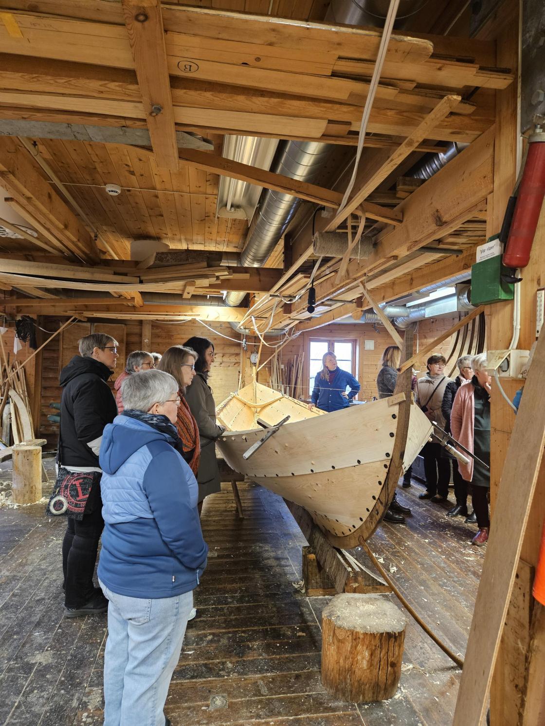 Damer rundt ein trebåt under bygging