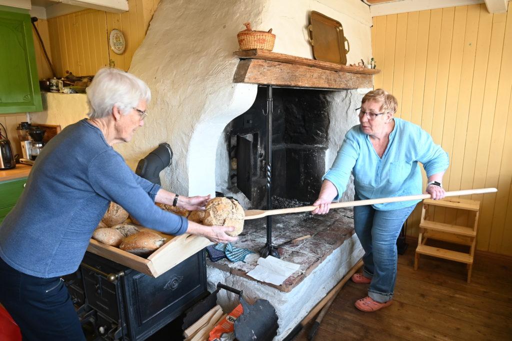 VEDFYRT BAKST: Liv Bruskeland Holm (t.v.) og Tora Ottersland holder den gamle tradisjonen i hevd. Tørrgran er viktig for riktig steketemperatur.