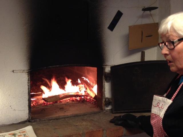 Inger Nygård fyrer opp bakerovnen. Foto Trine Evensen